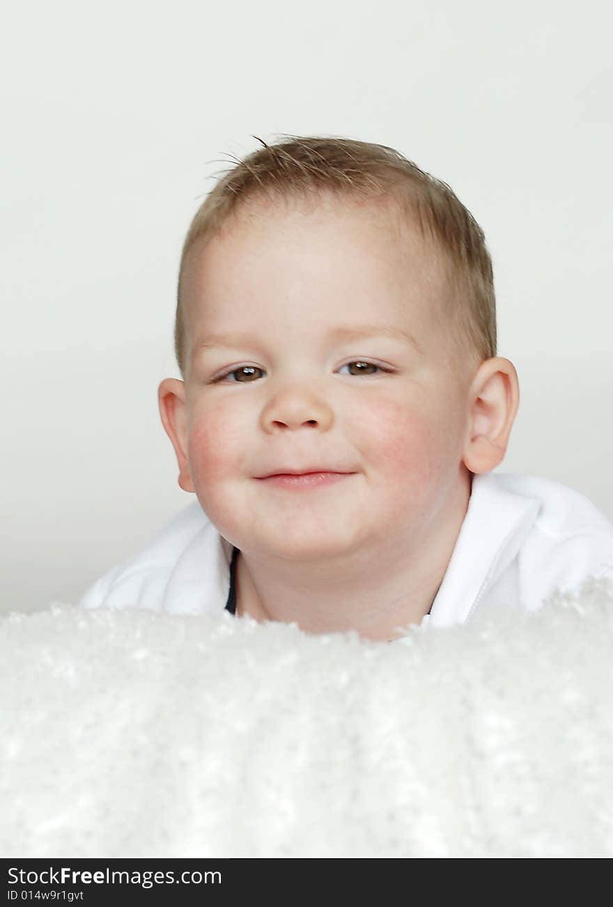 A young baby is smiling at the camera in a studio.  Vertically framed shot. A young baby is smiling at the camera in a studio.  Vertically framed shot.