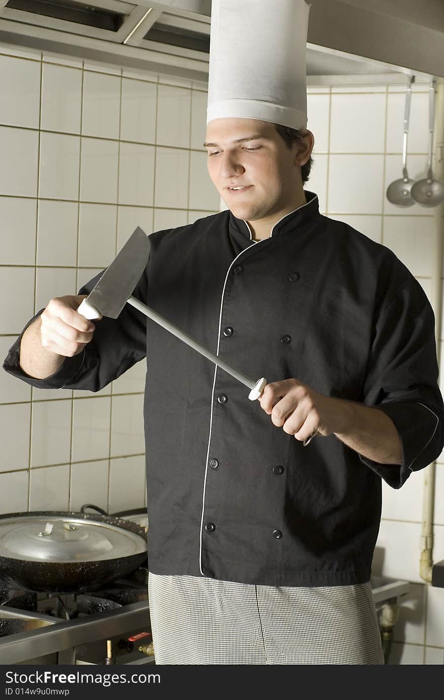 Chef sharpening a knife with a serious look on his face. Vertically framed photo. Chef sharpening a knife with a serious look on his face. Vertically framed photo.