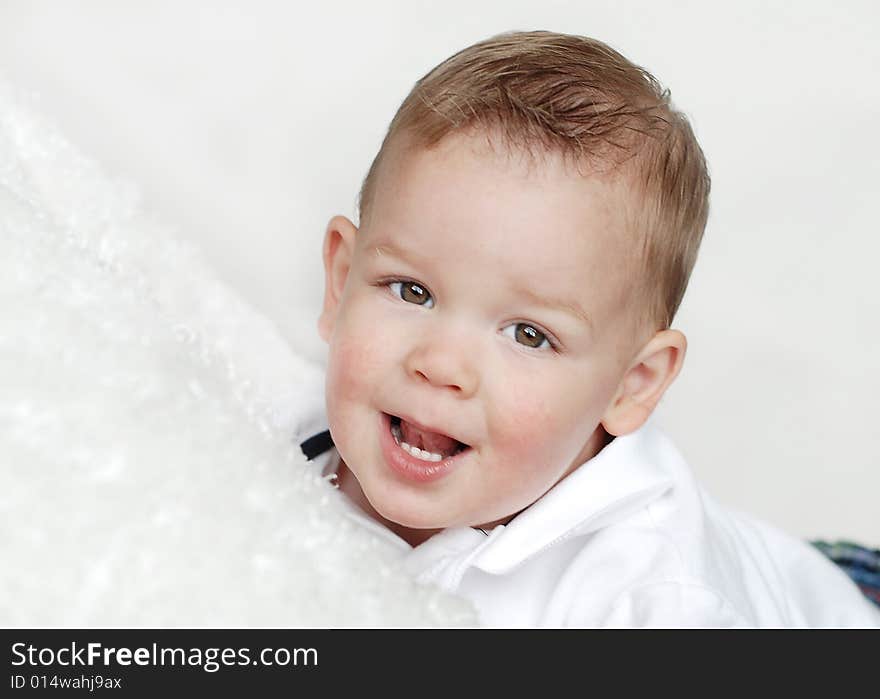 A young baby is smiling at the camera in a studio.  Horizontally framed shot. A young baby is smiling at the camera in a studio.  Horizontally framed shot.