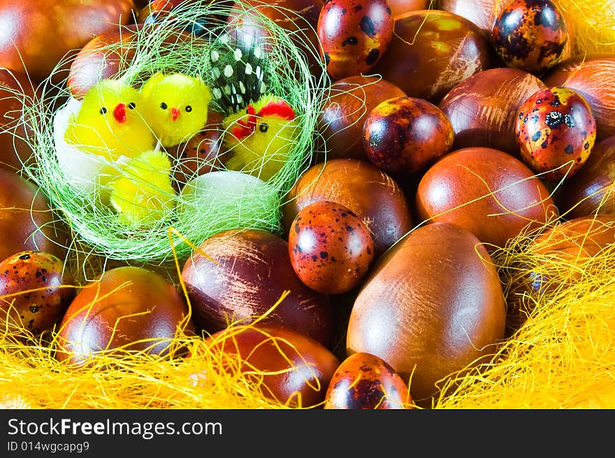 Small yellow chicks in basket full of painted brown Easter eggs. Small yellow chicks in basket full of painted brown Easter eggs