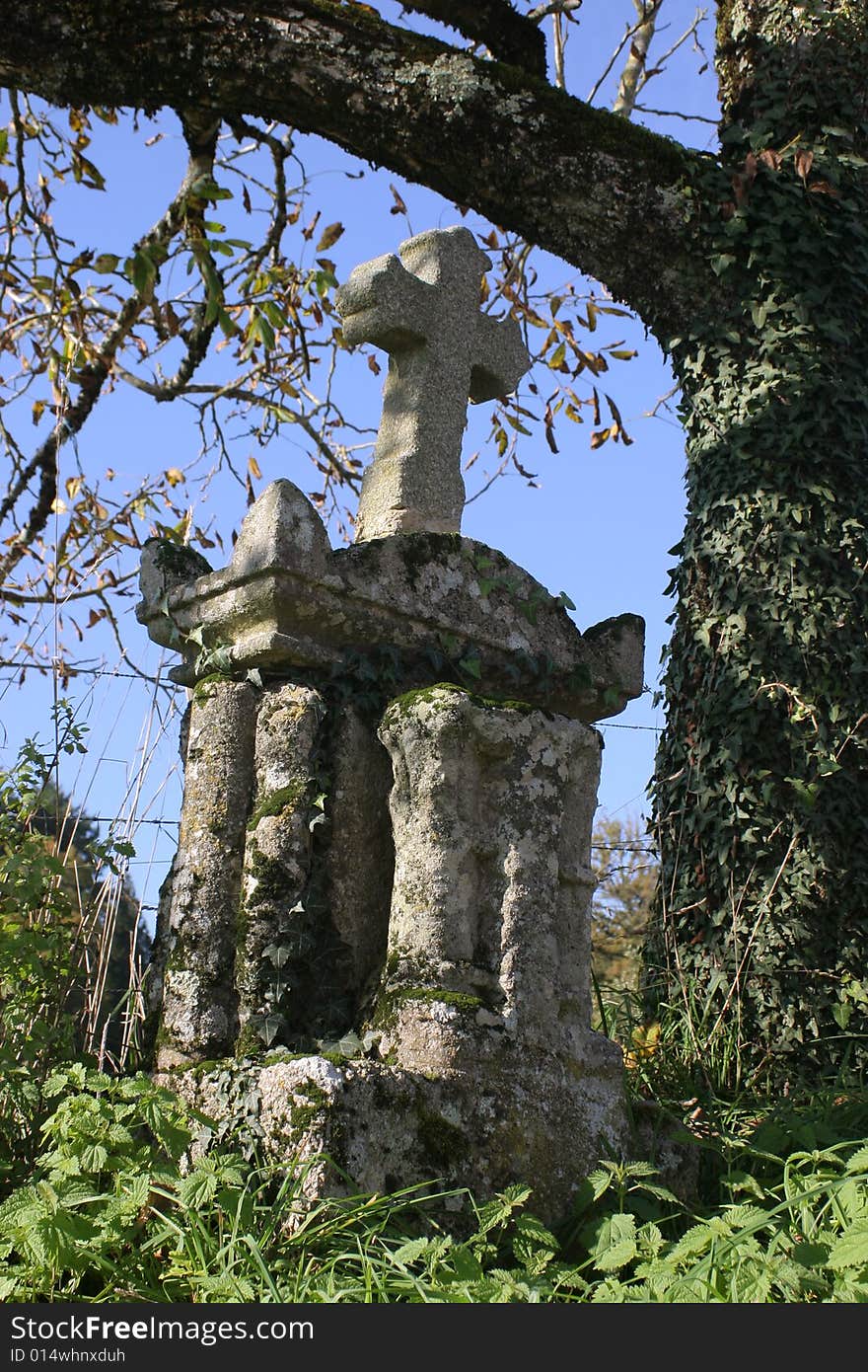 A very old catholic cross in granite at the countryside in France