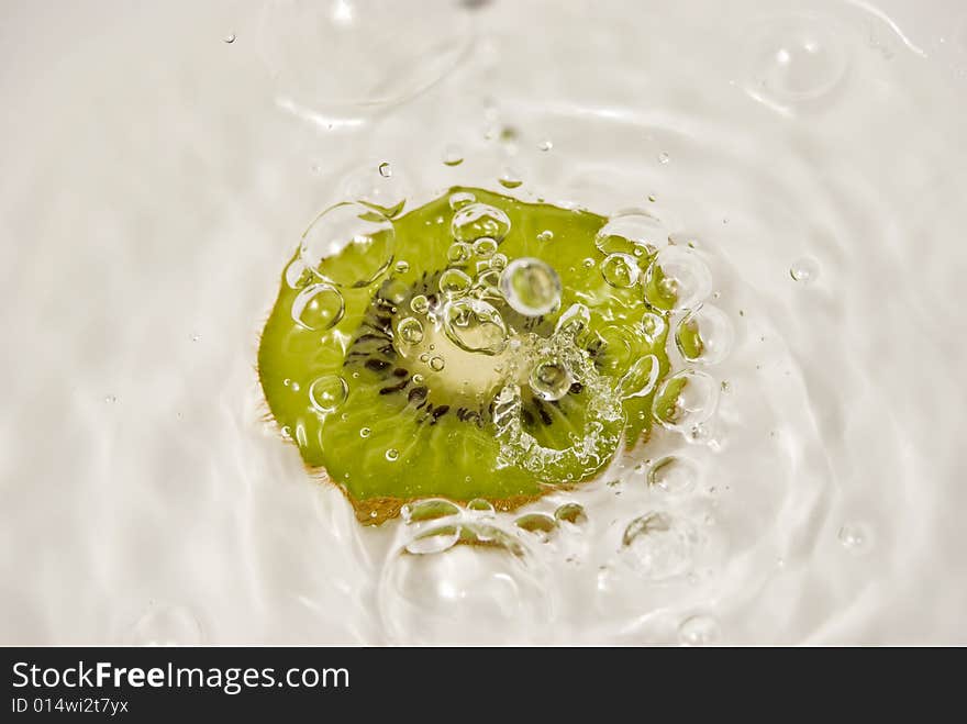 Slice of kiwi fruit and water on white background