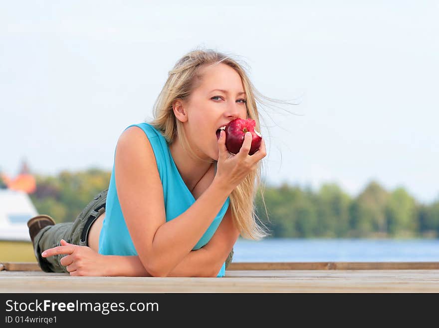 The girl overlies the foot-bridge and reaches for the apple. The girl overlies the foot-bridge and reaches for the apple