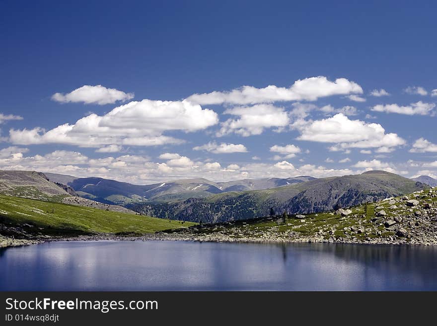 Lake in high mountains of Altai, summer, blue sky and white clouds