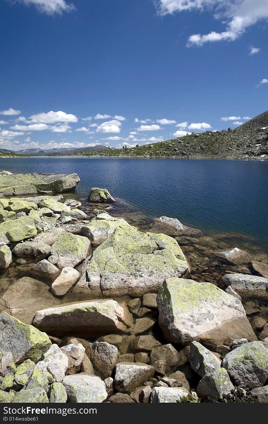 Lake in high mountains of Altai, summer, blue sky and white clouds