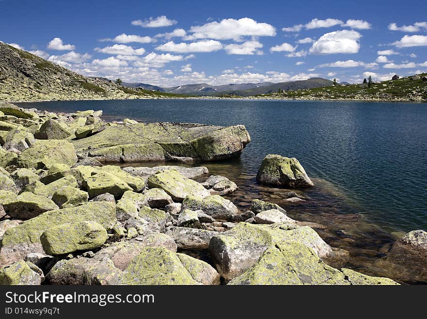 Lake in high mountains of Altai, summer, blue sky and white clouds