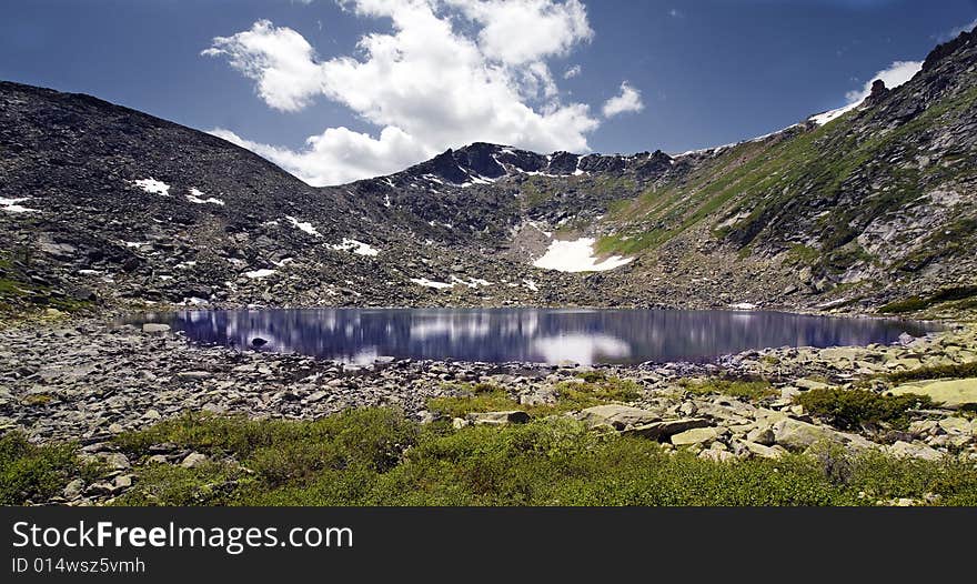 Lake in high mountains of Altai, summer, blue sky and white clouds