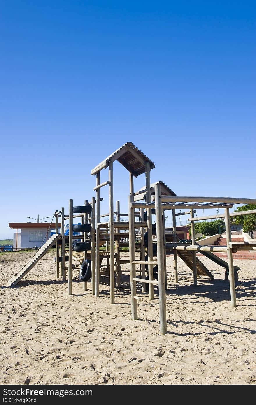 A park next to the beach with a play area for kids containing a wooden jungle-jim. A park next to the beach with a play area for kids containing a wooden jungle-jim.