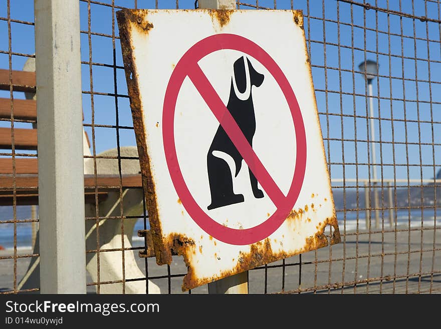 An old rusty sign, indicating that no dogs are allowed on the beach. An old rusty sign, indicating that no dogs are allowed on the beach.