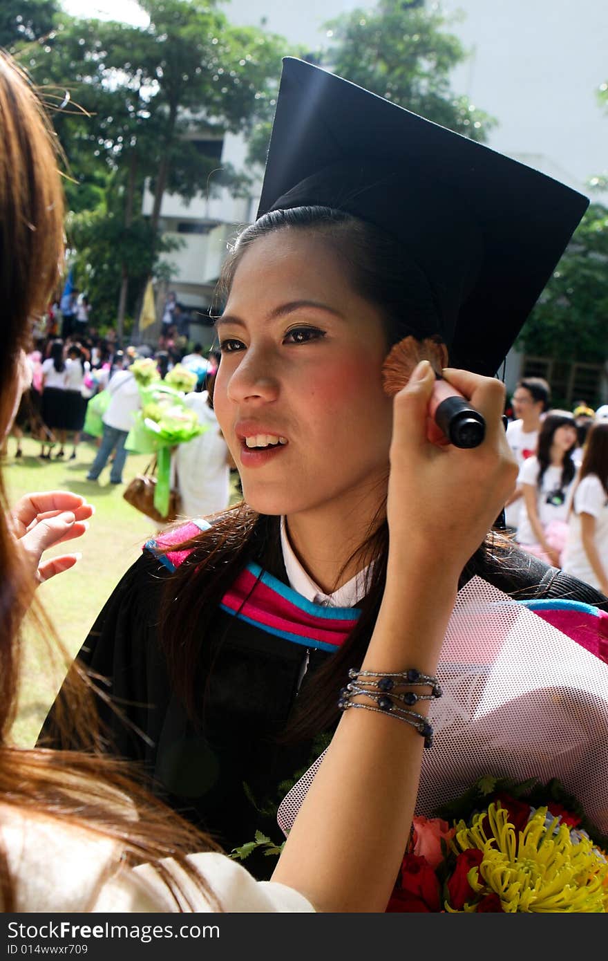 Beautiful young Asian graduate having her make-up done for graduation day.