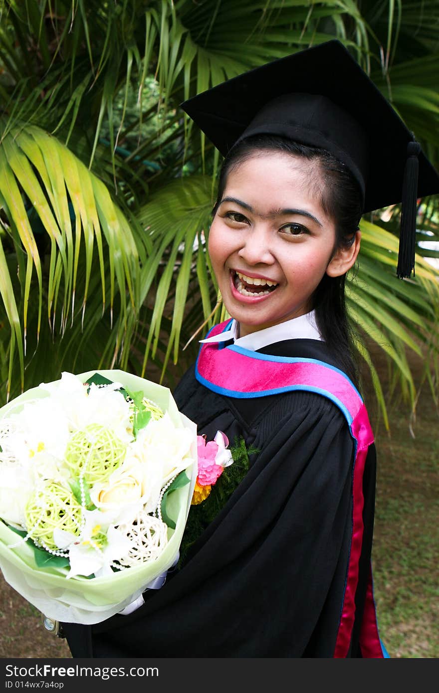 Beautiful young Asian graduate in robes on graduation day.