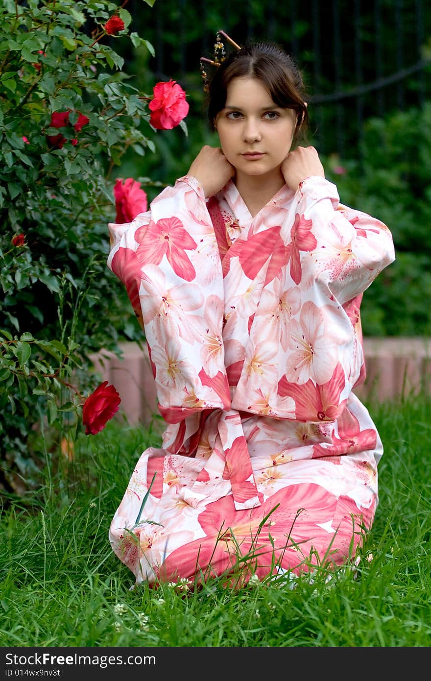 Girl in a pink yukata near rosebush. Girl in a pink yukata near rosebush