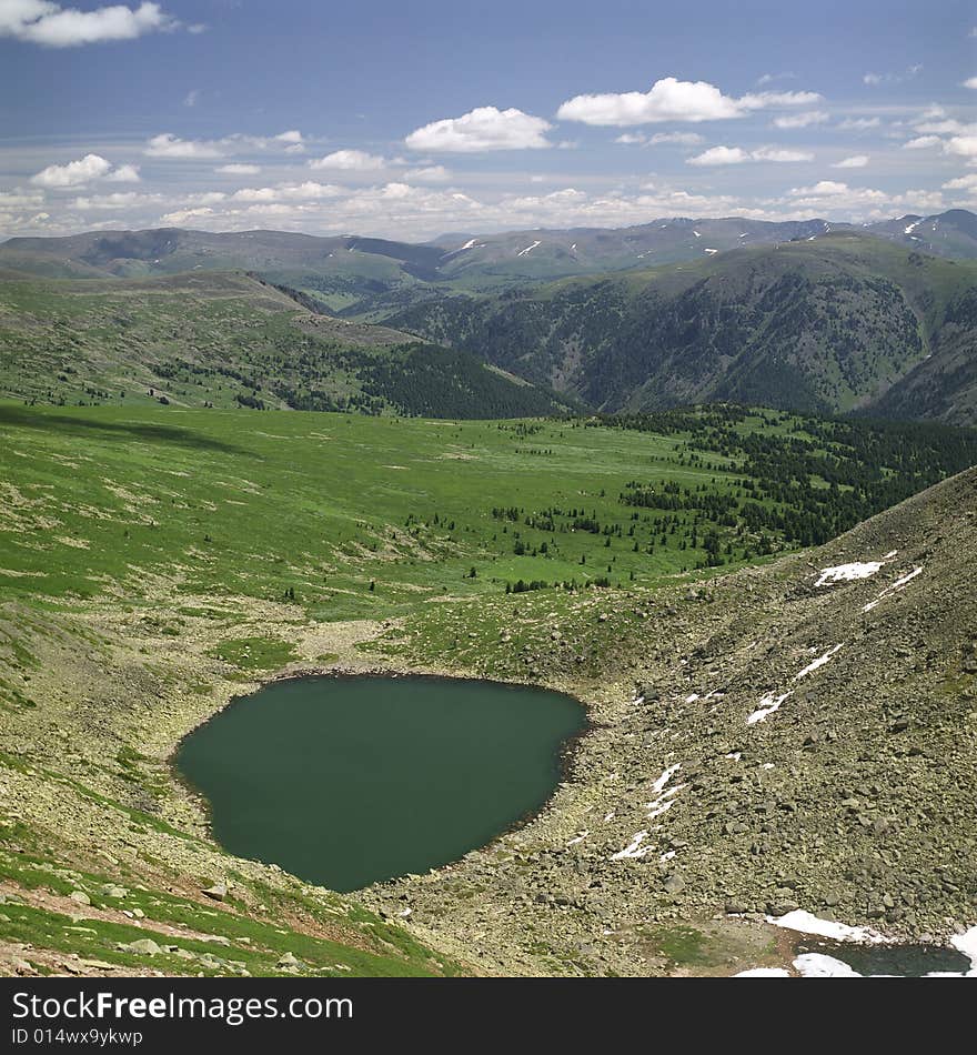 Lake in high mountains of Altai, summer, blue sky and white clouds