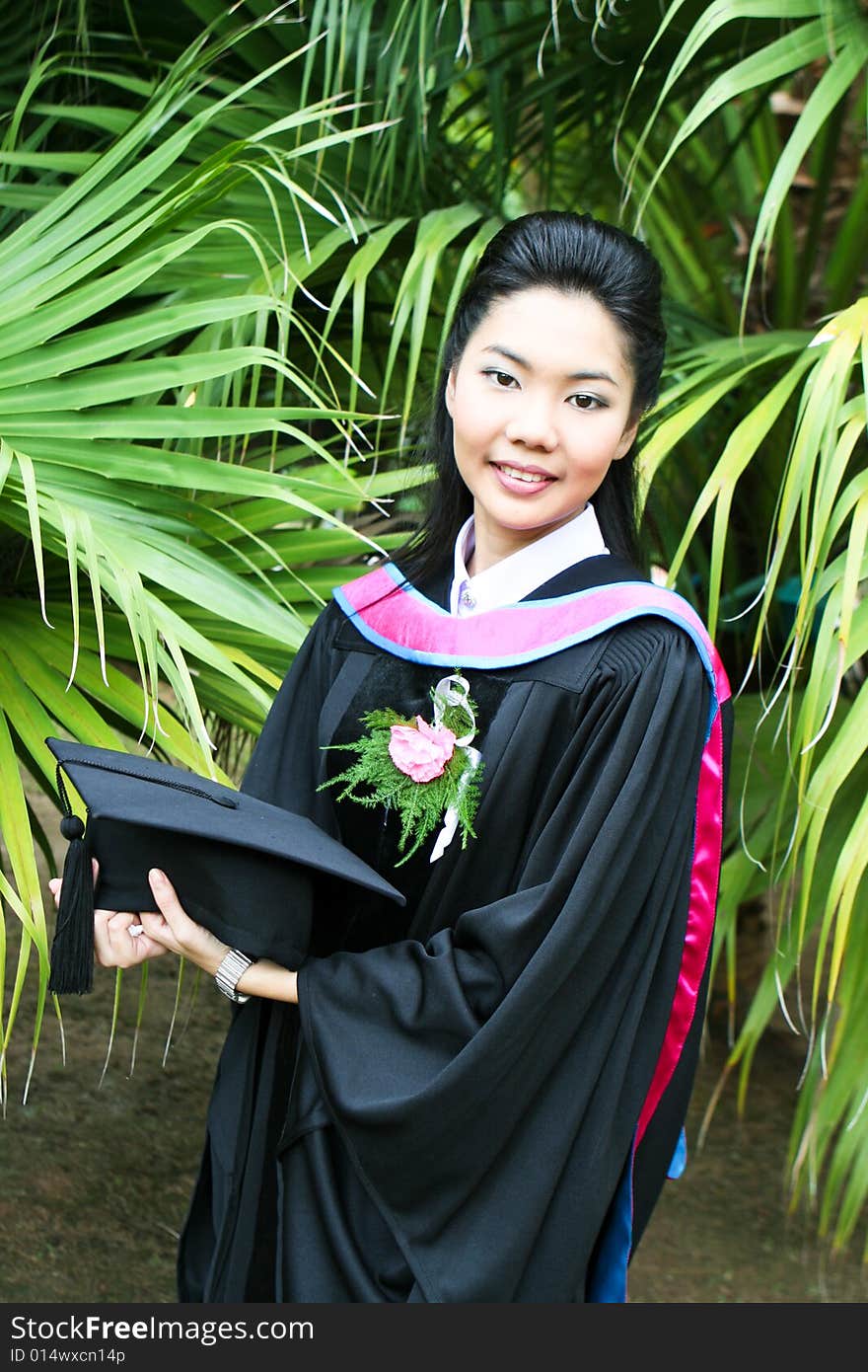 Beautiful young Asian graduate in robes on graduation day.