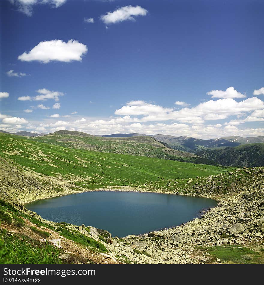 Lake in high mountains of Altai, summer, blue sky and white clouds