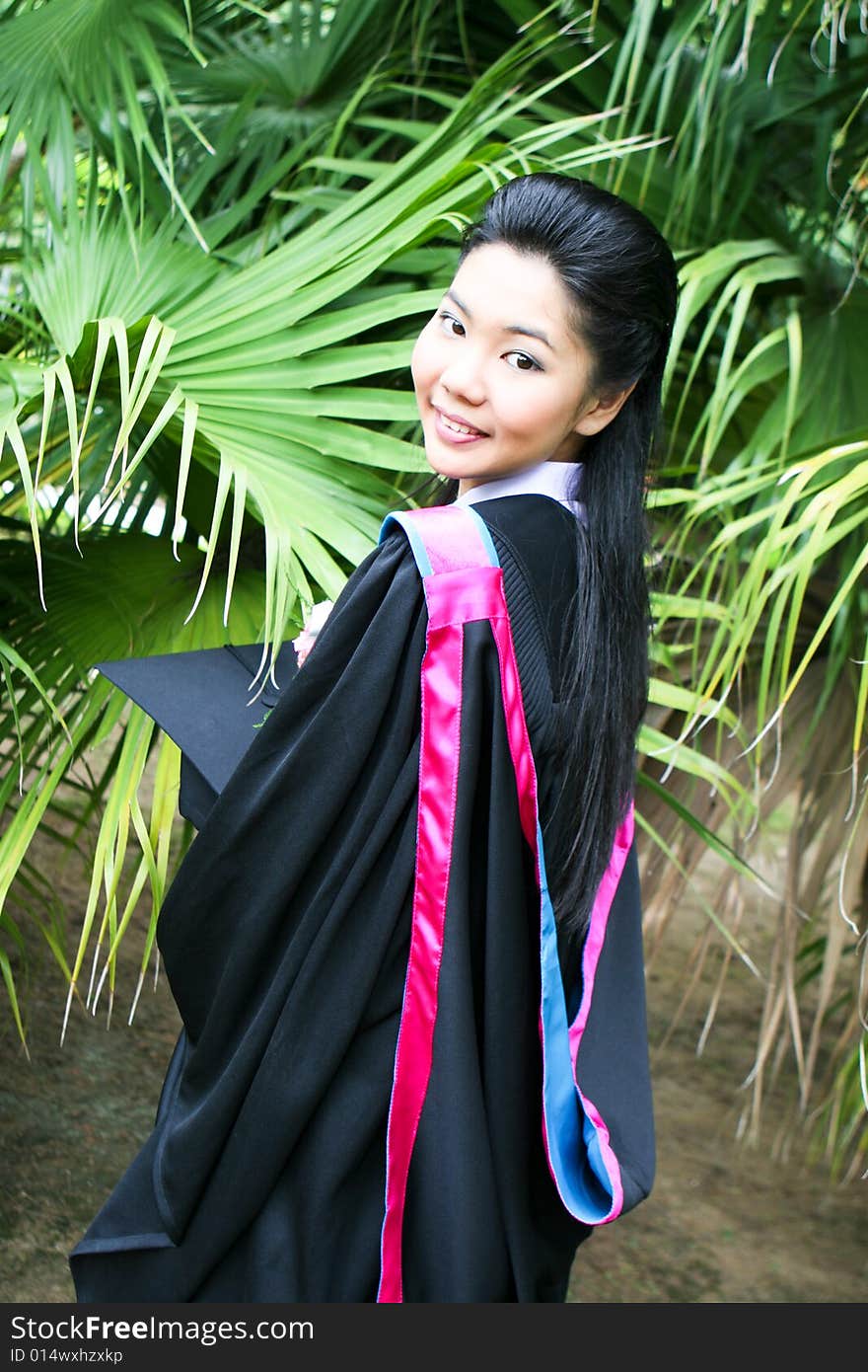 Beautiful young Asian graduate in robes on graduation day.