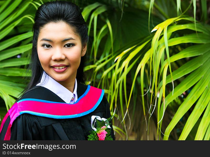 Beautiful young Asian graduate in robes on graduation day.