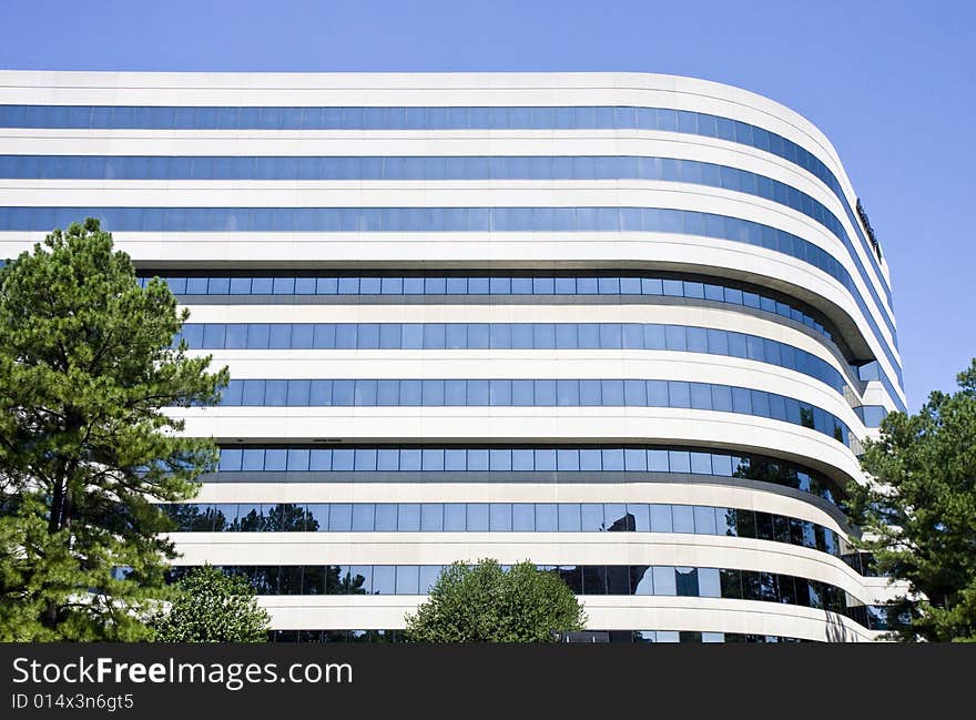 A modern concrete and glass building curving against a blue sky