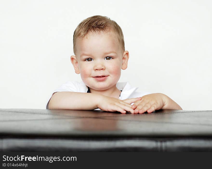 A young baby is posing for the camera in a studio.  Horizontally framed shot. A young baby is posing for the camera in a studio.  Horizontally framed shot.