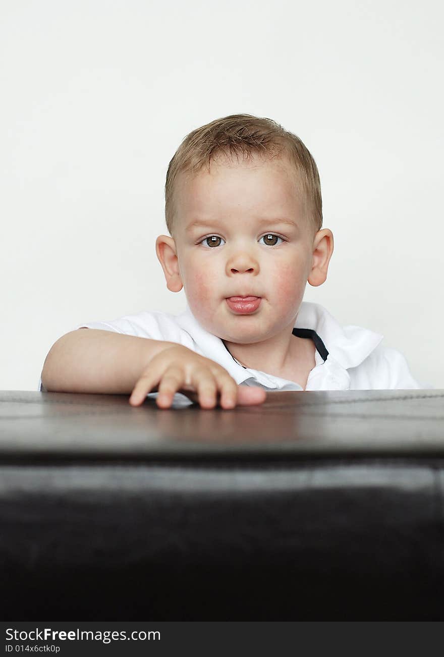 A young baby is posing for the camera in a studio.  Vertically framed shot. A young baby is posing for the camera in a studio.  Vertically framed shot.