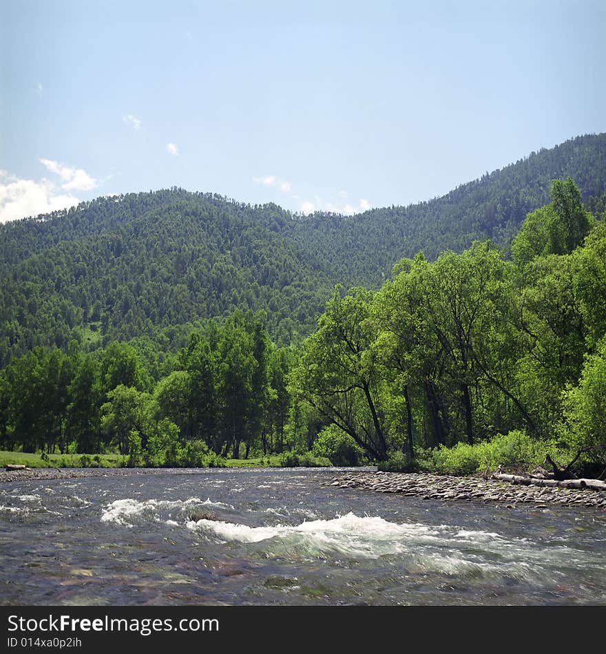 River flow in high mountains, green grass, water and clouds