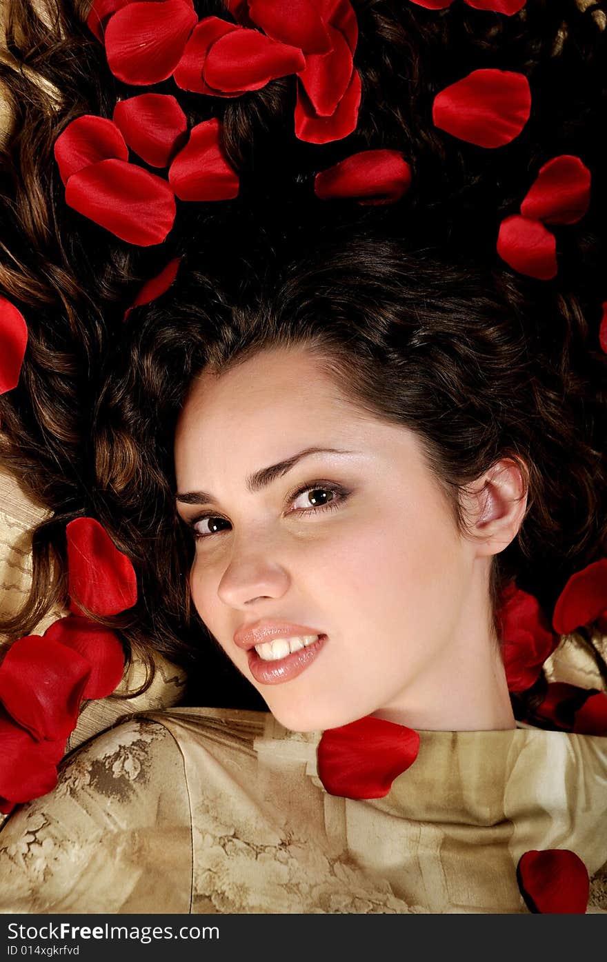 Beautiful woman with red rose petals on golden background. Beautiful woman with red rose petals on golden background