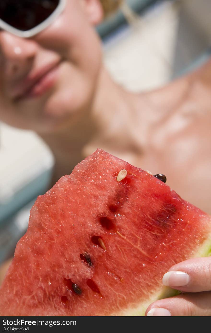 Portrait of young beautiful woman eating a watermelon