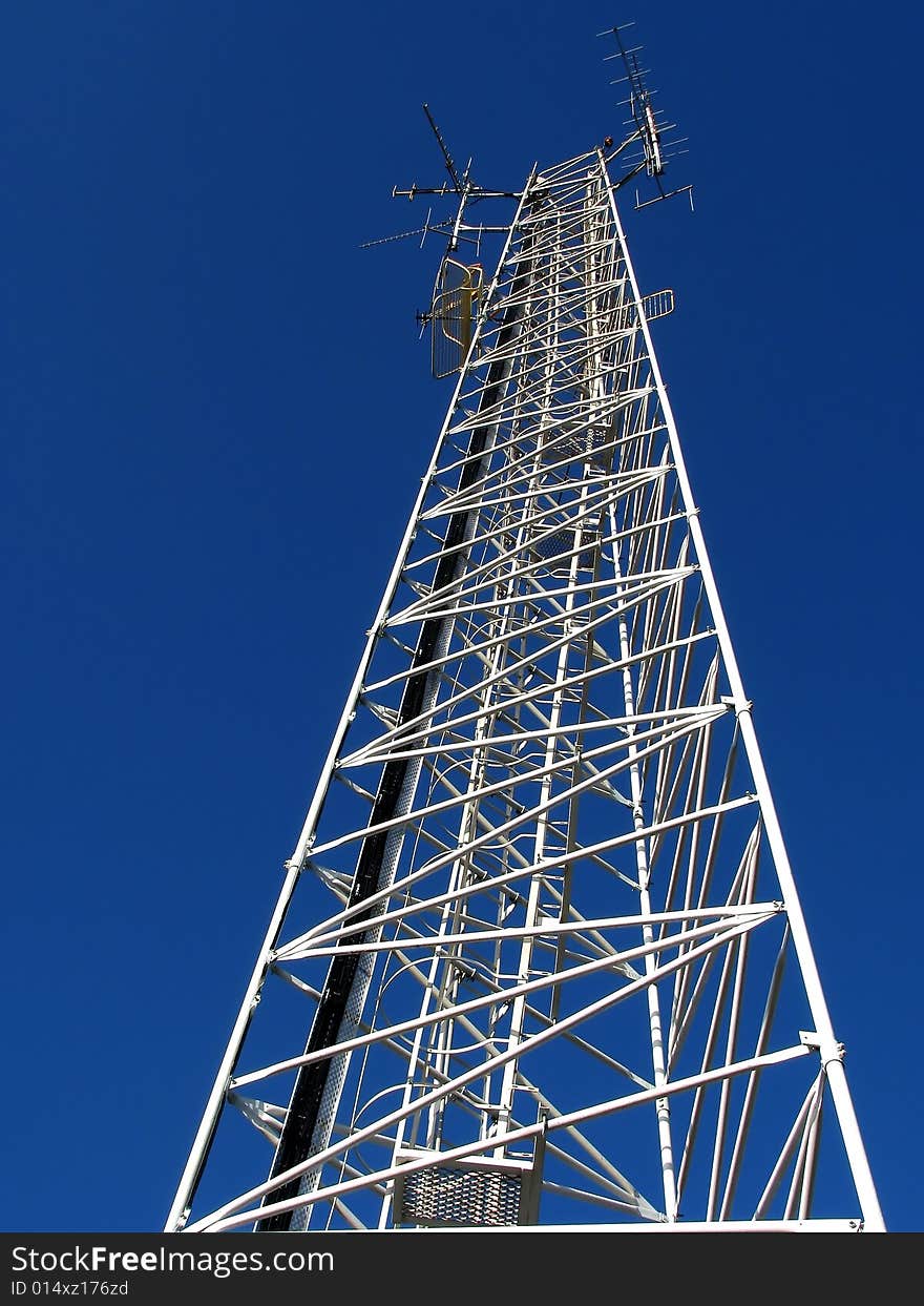 Tall white cellphone tower with blue sky