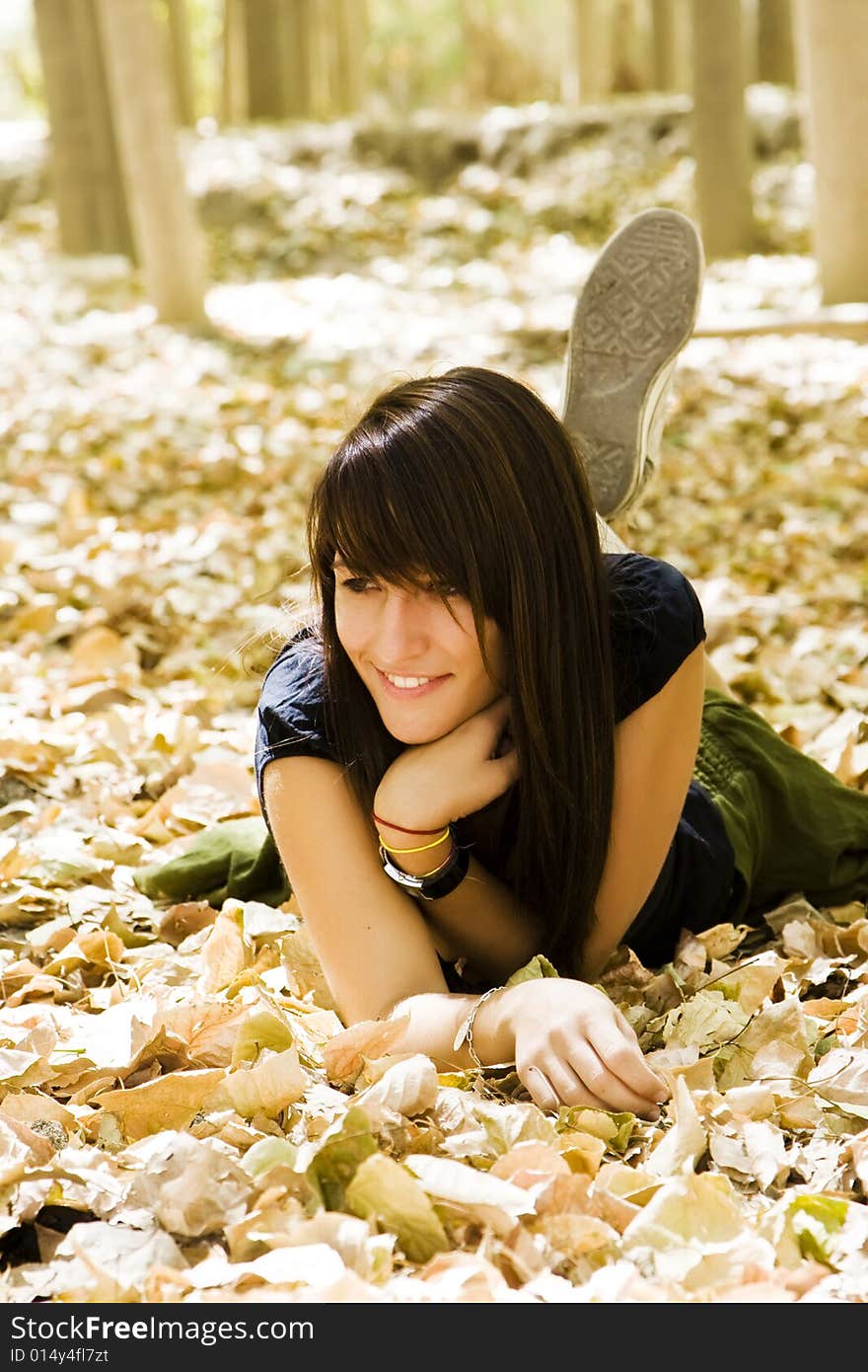 Young woman laying over fallen leaves. Young woman laying over fallen leaves.