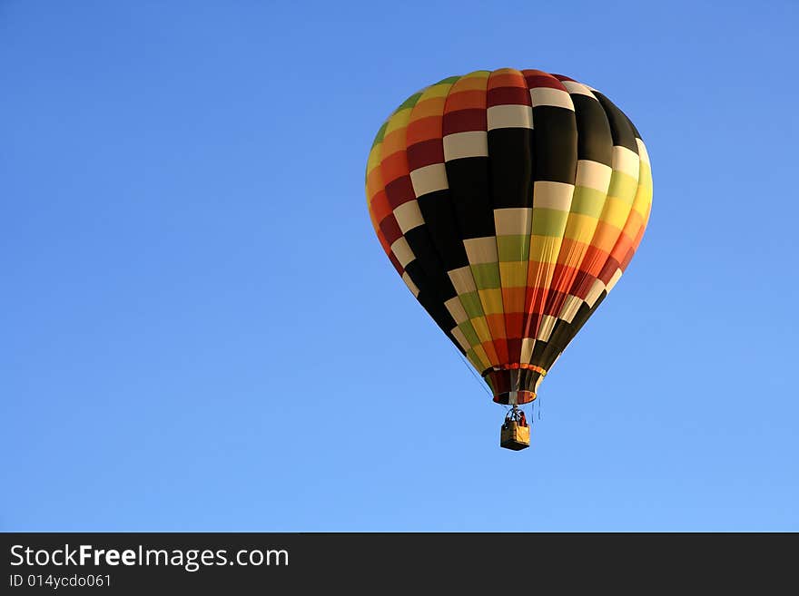 Multicoloured hot air balloon in the blue sky.