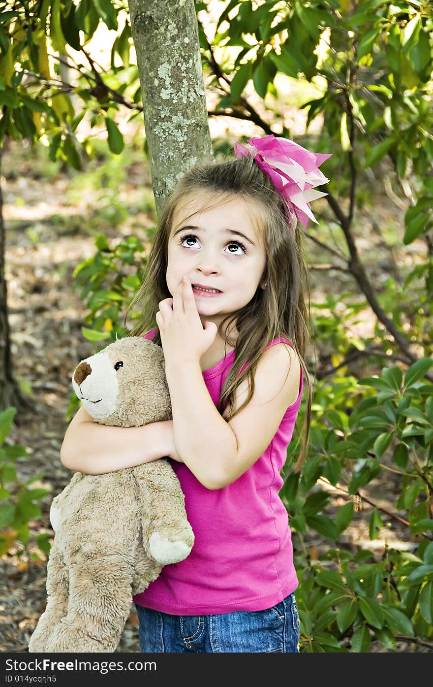 Little girl looking up with her hand next to her mouth, thinking and holding her best friend, her teddy bear. Little girl looking up with her hand next to her mouth, thinking and holding her best friend, her teddy bear.