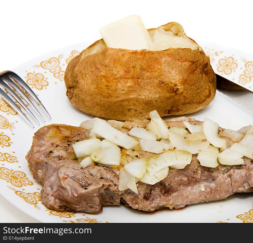 A grilled steak smothered with onions with a hot buttered baked potato. A grilled steak smothered with onions with a hot buttered baked potato