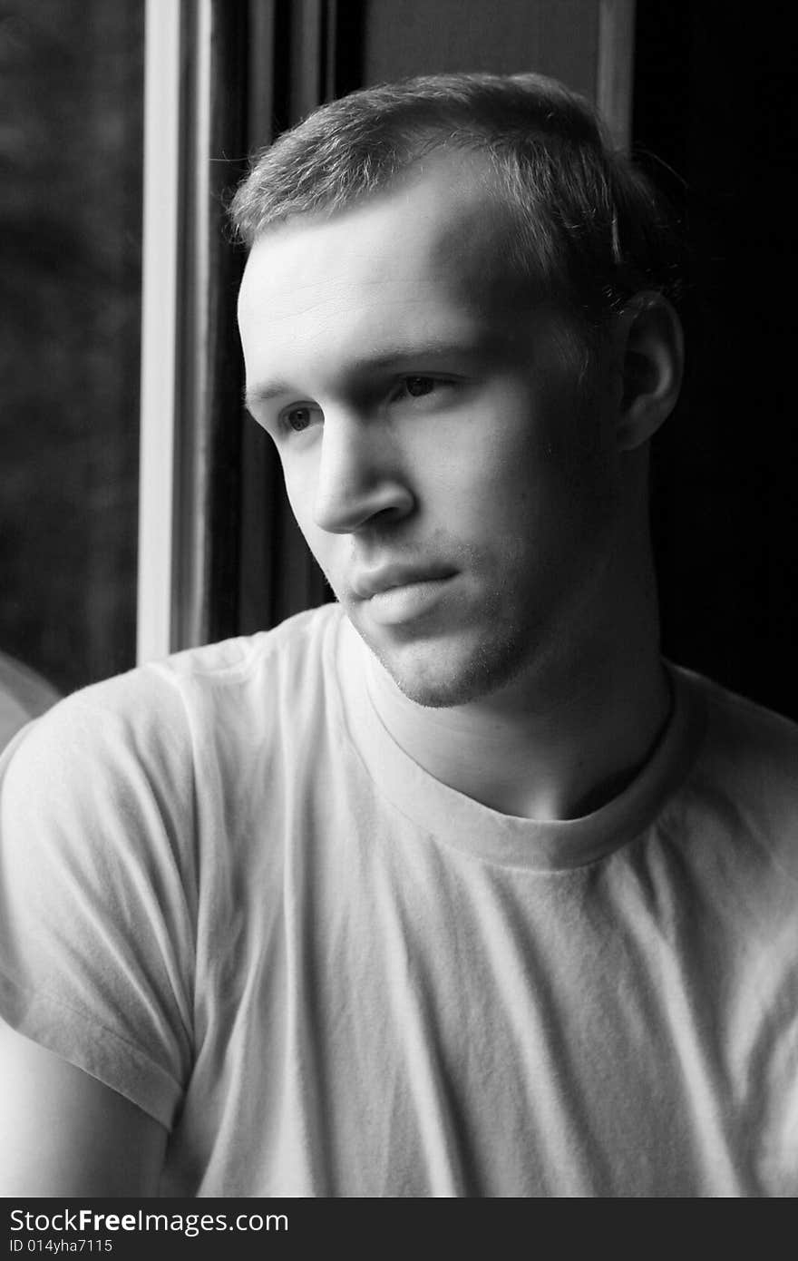 Natural light portrait of man in t-shirt at a window. Natural light portrait of man in t-shirt at a window