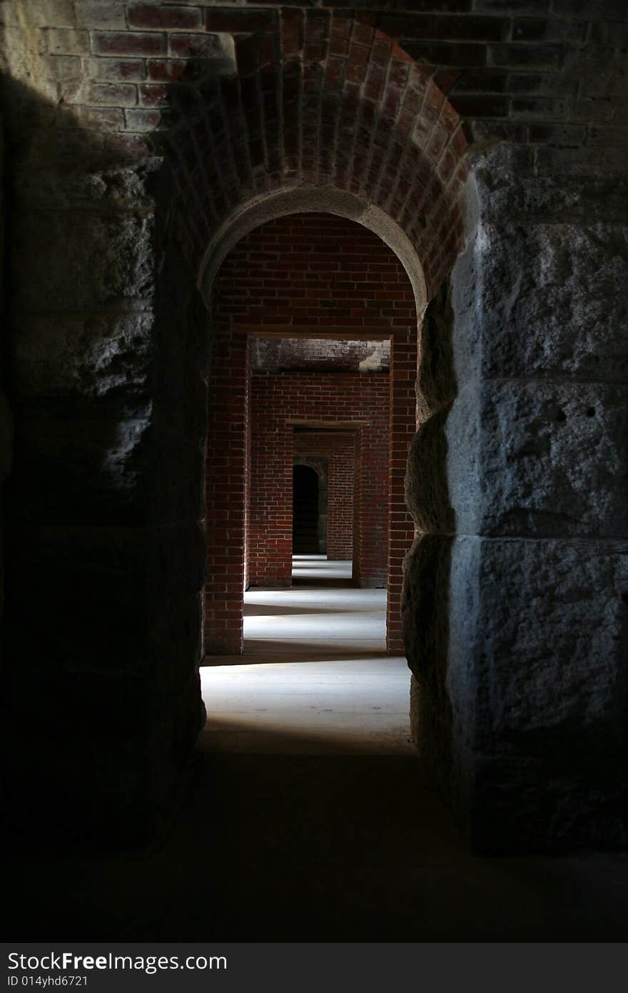 Looking down a stone and brick hallway with sunlight and shadows. Looking down a stone and brick hallway with sunlight and shadows