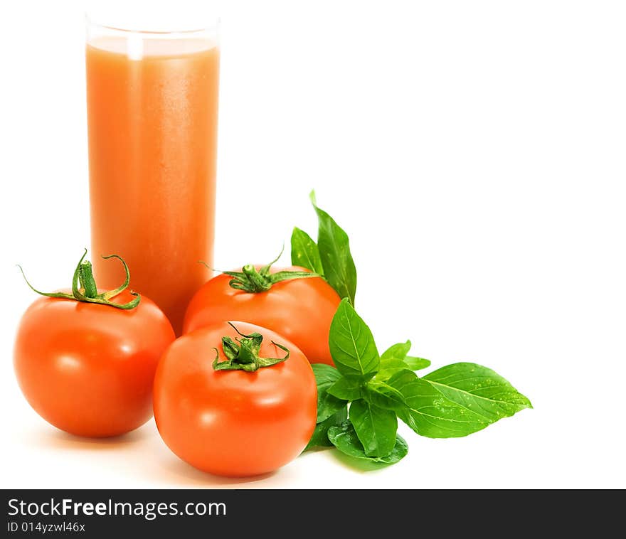 Fresh tomatoes with basilico herb and glass of tomato juice over white