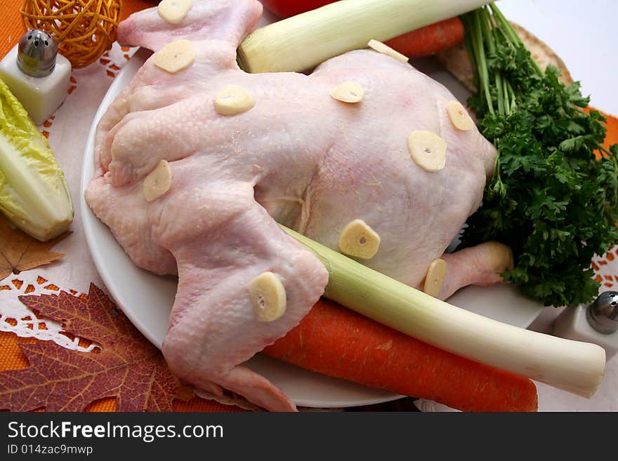 A fresh chicken and some vegetables for cocking a soup