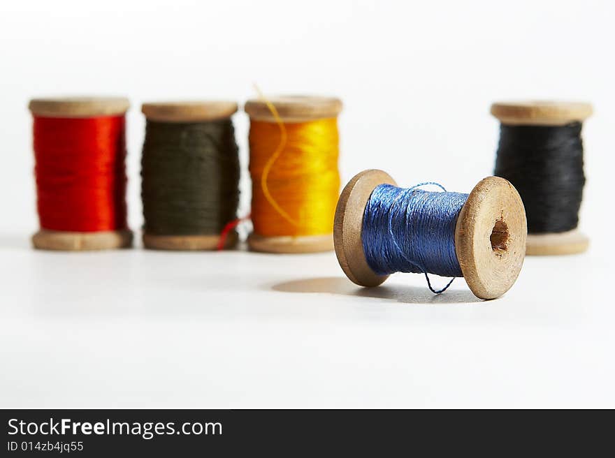 Group of 5 color spools of thread on white background