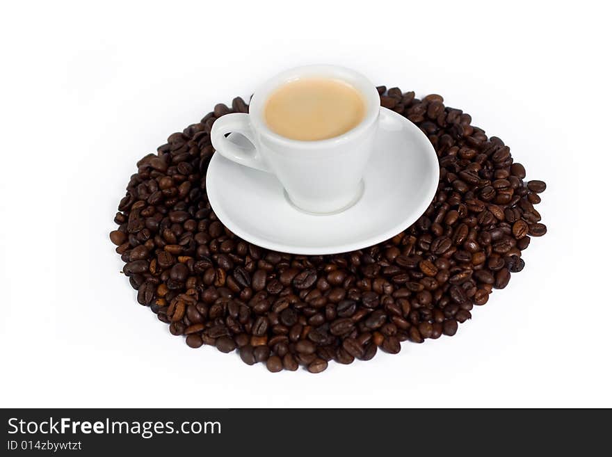 A cup of coffee on top of coffee beans isolated on white