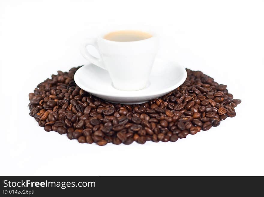 A cup of coffee on top of coffee beans isolated on white