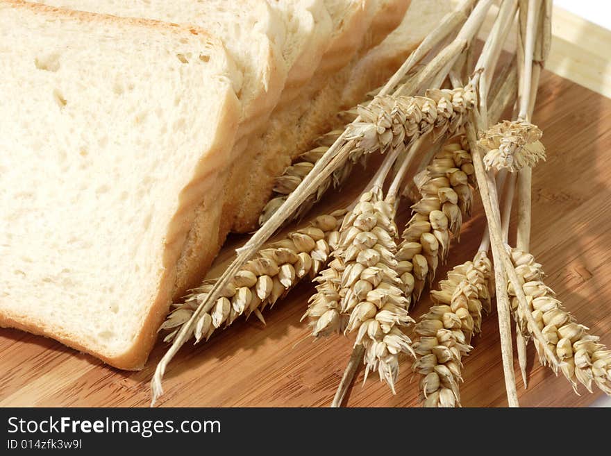 Toast slices and wheat ears on a kitchenboard