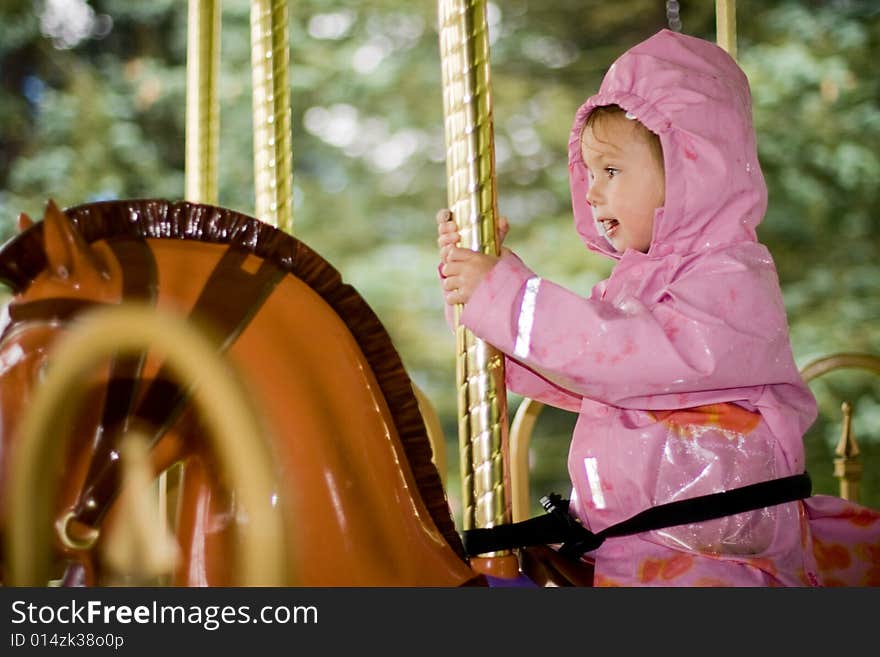 Little beauty girl on merry-go-round in the rain. Little beauty girl on merry-go-round in the rain