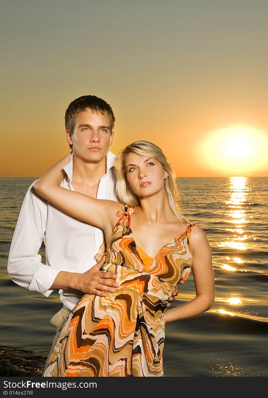 Young couple in love near the ocean at sunset