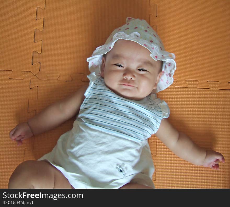 Pretty baby is smiling on a yellow mat