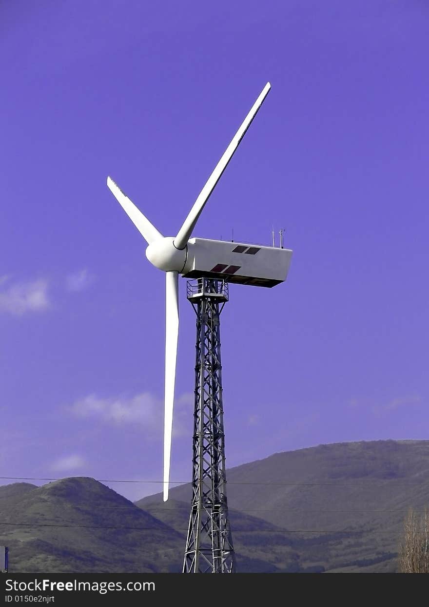 View of wind turbine against blue sky and clouds.