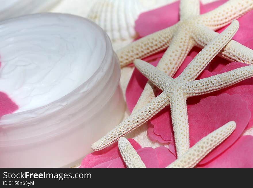 Body cream with soap rose petals and starfishes on white towel, closeup. Body cream with soap rose petals and starfishes on white towel, closeup