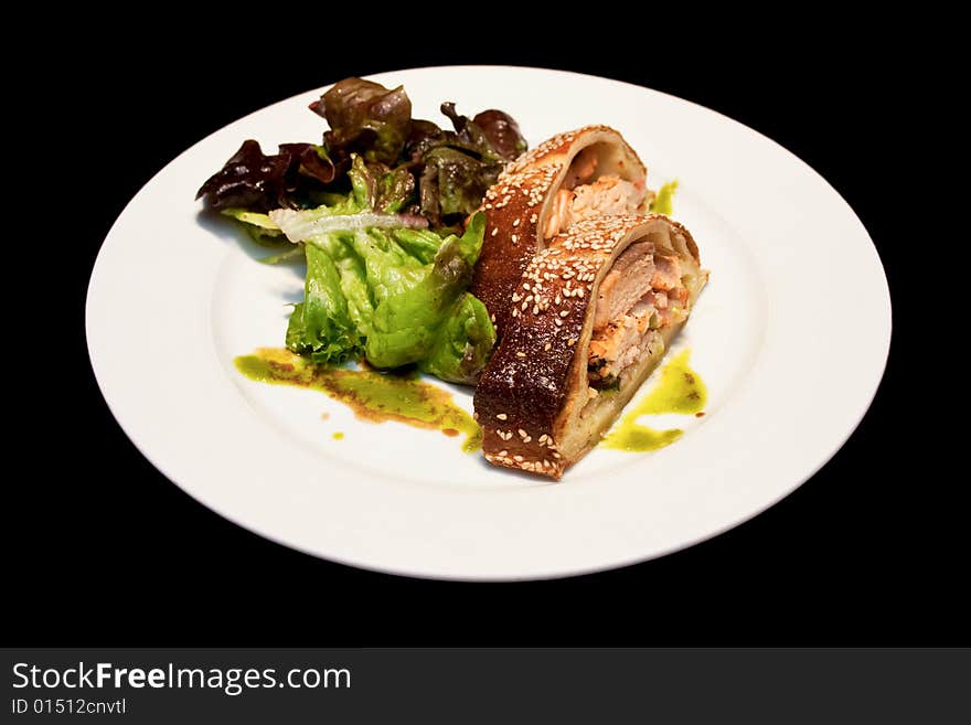 Salmon strudel on a white plate isolated on black