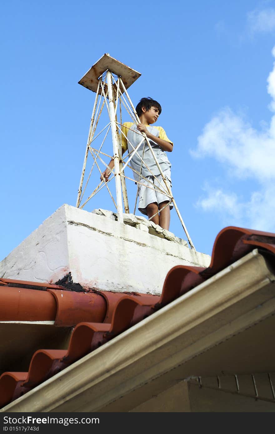 Young child holding on to a tower on the roof of his house. Young child holding on to a tower on the roof of his house.