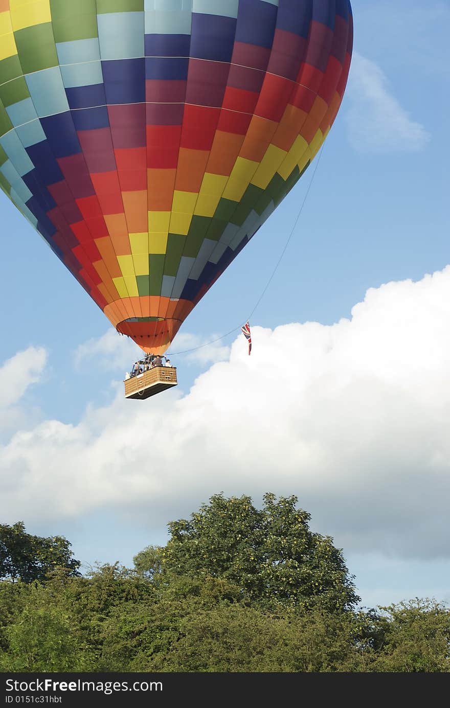 Taking off from a summer pasture in a multicolored hot air baloon. Taking off from a summer pasture in a multicolored hot air baloon