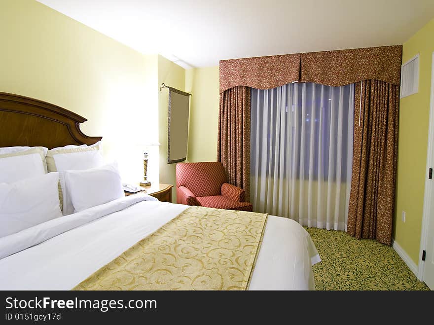 Partial view of bed and chair with curtains and window in background