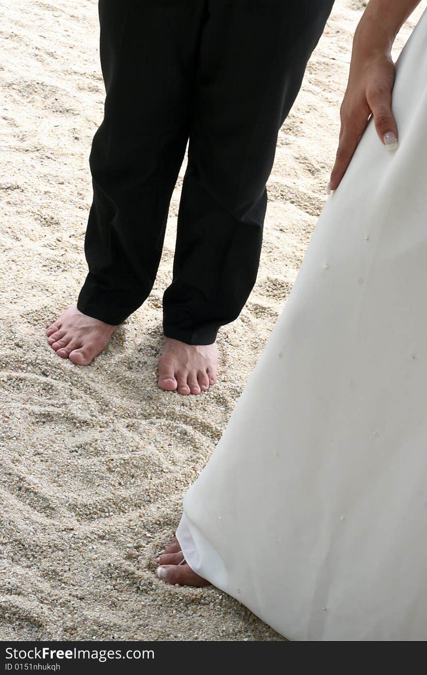 Bride and groom next to a love heart pattern in the sand.